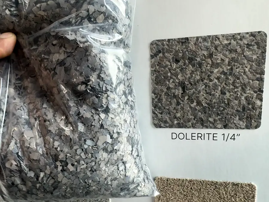 A bag of gray flakes beside a flake sample board labeled Dolerite 1/4 inch