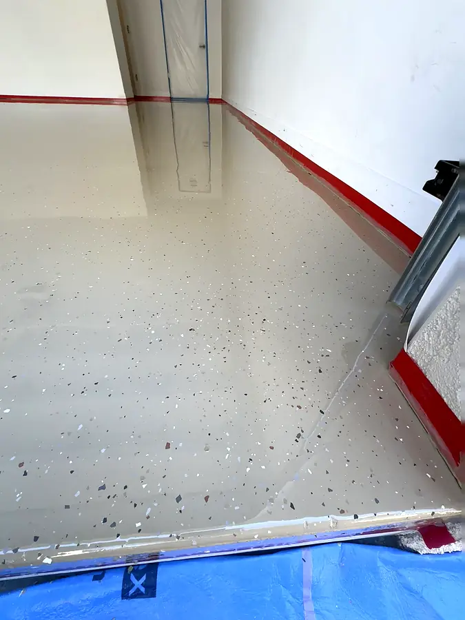 Pails of a two-part moisture vapor barrier coating stacked in a garage corner