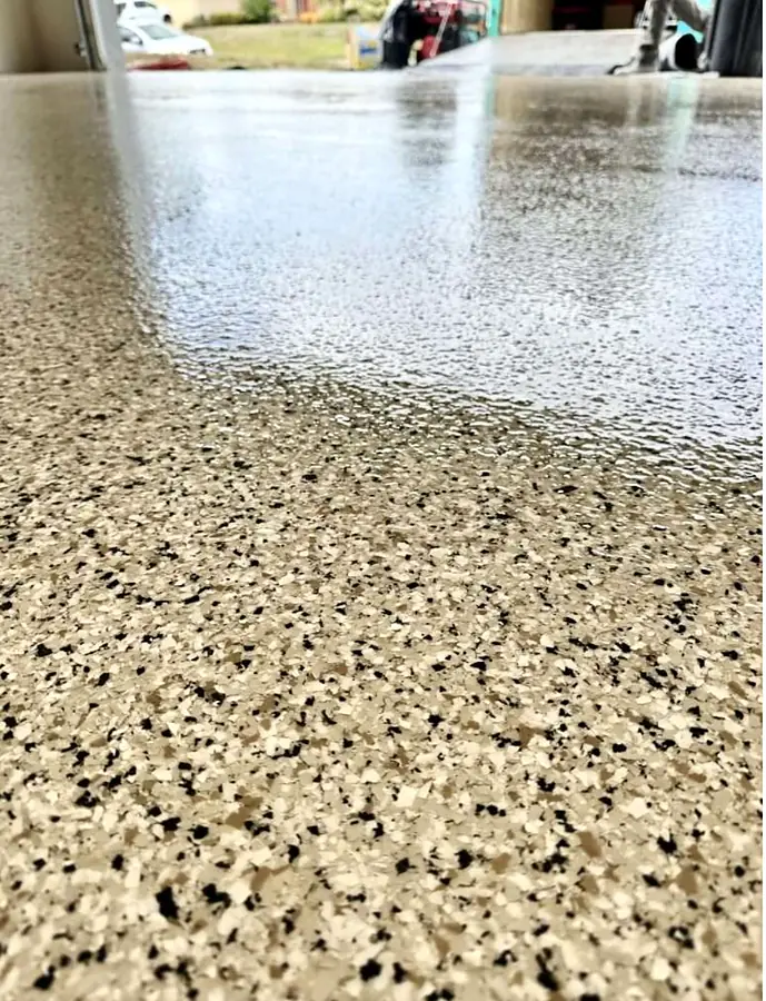 Close view of a tan, black and white flake epoxy floor with a glossy finish