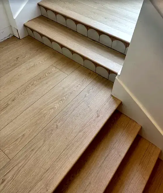 Light oak stair treads with scalloped white tile on the risers, turning at a landing
